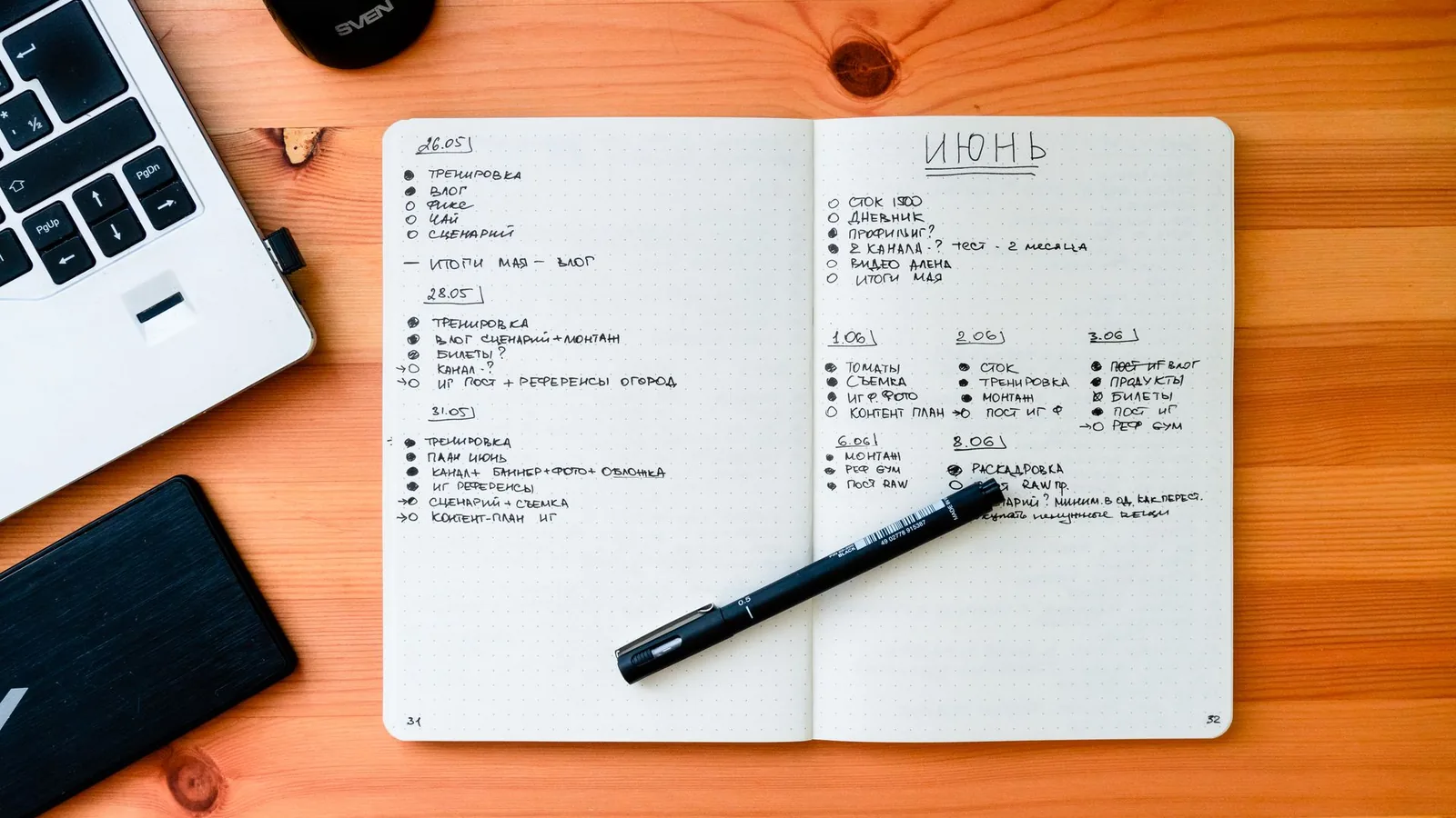 Open notebook with handwritten notes next to a laptop on a wooden desk